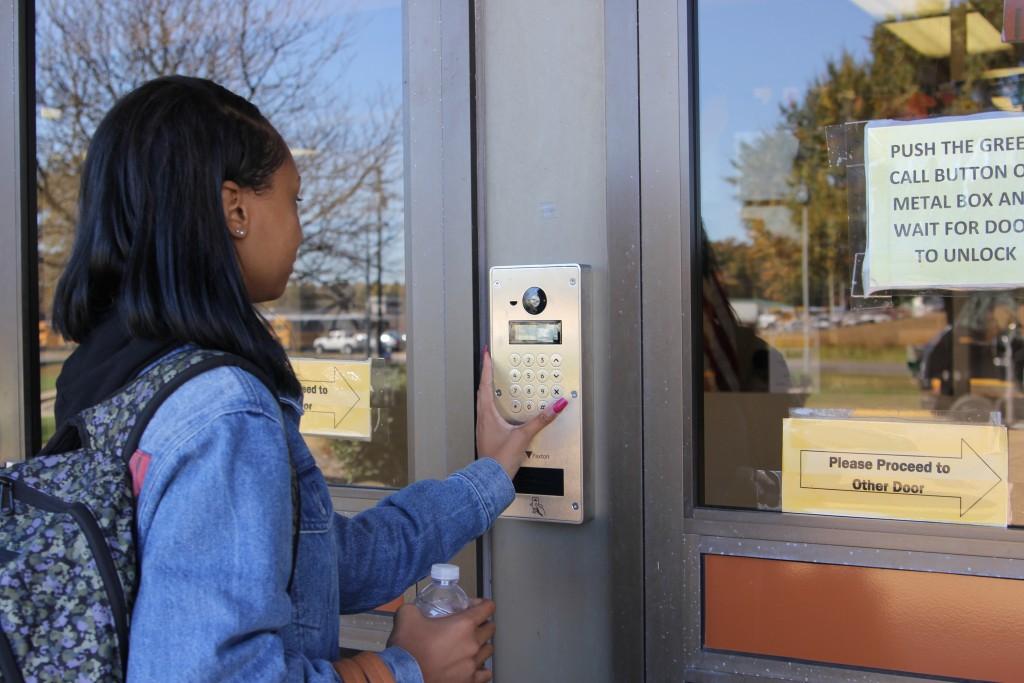 Senior Jacqueline Mckay pushes the green button to alert the front desk to unlock the front door. 
Photo by Hydeia Nutt