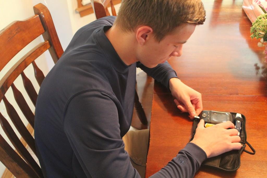 Senior Logan Chadek checks his blood sugar levels with his  test kit, Omnipod.
Chadek was diagnosed with diabetes at 13 months old.
Photo by April Buckles.