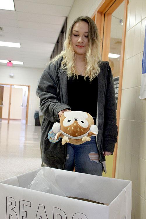 Junior Brianna Barlow puts a stuffed animal in the box. These toys will be distributed on December 20th. Photo by Shelby Hayes.