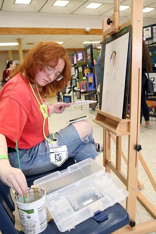 Junior Annabelle Starr at Spring Fling working on her painting. Starr worked on the piece throughout the event.  
Photo  by Emily Hannuksela.